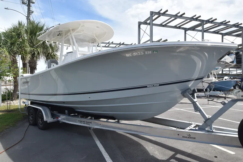 Slide: The Image of A 2018 Regulator 28 Forward Seating boat on a trailer in a parking lot. - 3