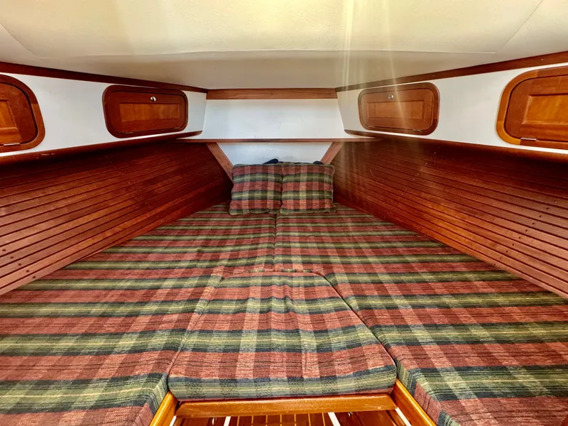 Slide: The Image of The cabin of the 2003 Legacy 34 Express features a cozy bed with striped bedding. - 39