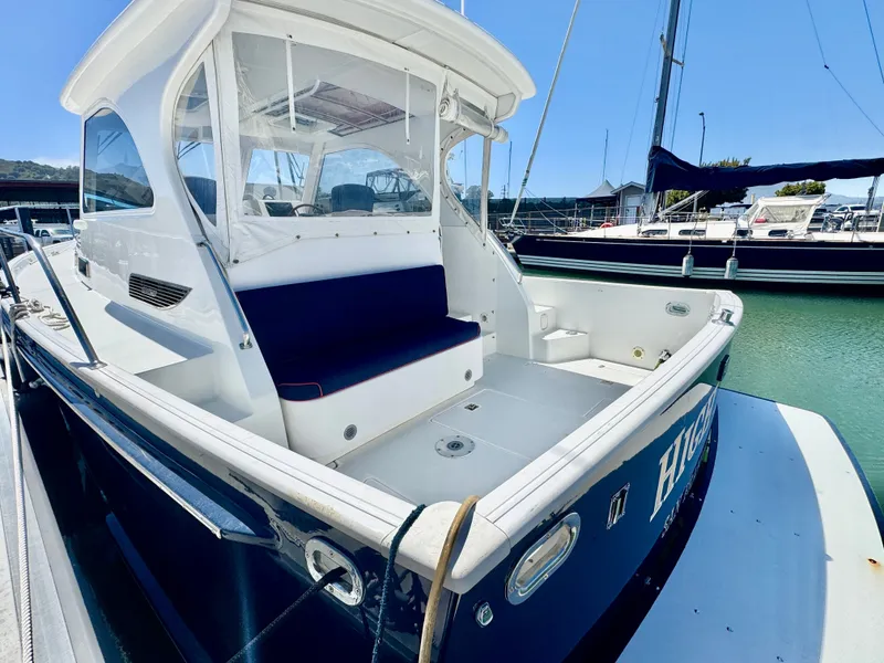 Slide: The Image of A 2003 Legacy 34 Express docked in a marina. It features an open cockpit with blue seating. - 5