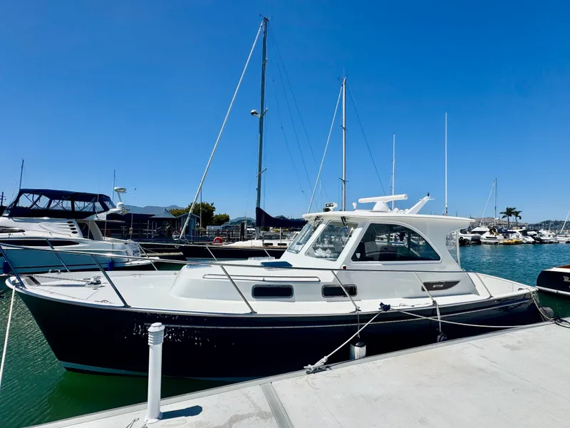 Slide: The Image of A 2003 Legacy 34 Express docked in a sunny marina with other boats. - 2