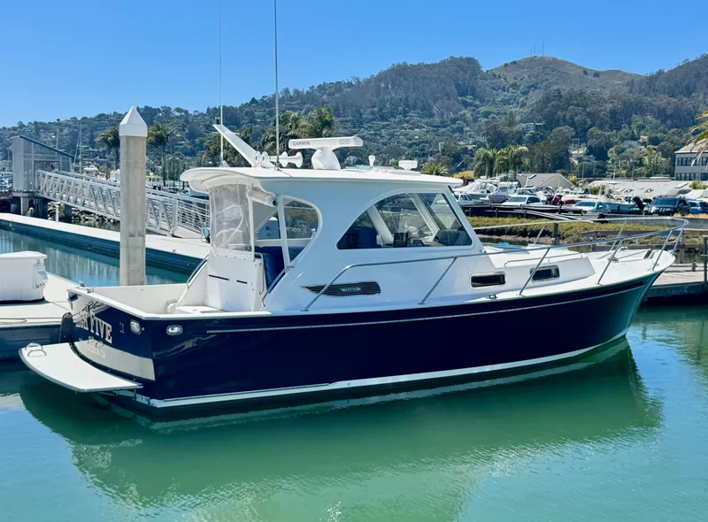 Slide: The Image of A 2003 Legacy 34 Express boat docked. It features a sleek white and blue design. - 0