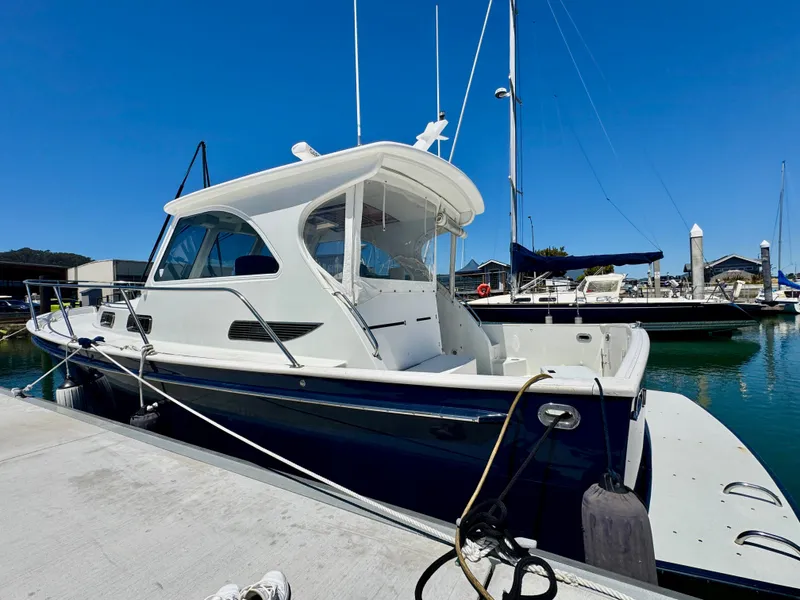 Slide: The Image of A 2003 Legacy 34 Express boat docked. It features a white canopy and blue hull sides. - 4