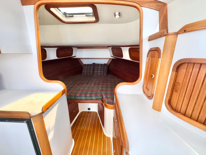 Slide: The Image of The cabin of a 2003 Legacy 34 Express with wood accents and a cozy bed. - 38