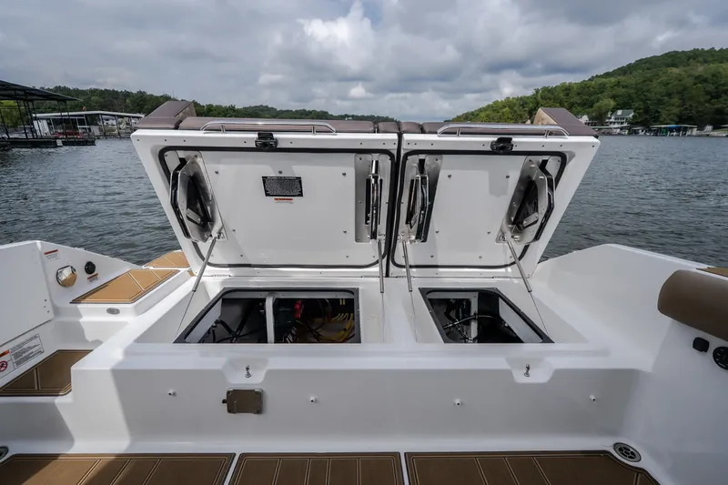 Slide: The Image of Open storage compartments on a 2026 Monterey Elite 30 OB boat, docked by a lake. - 47