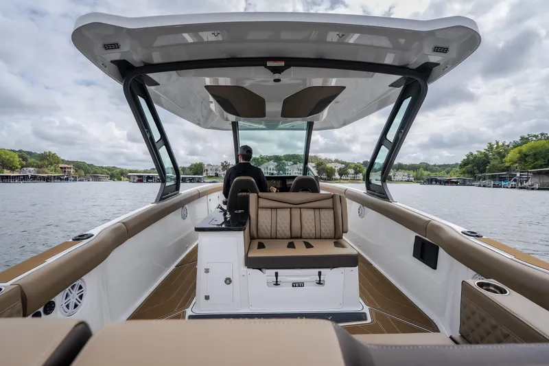 Slide: The Image of 2026 Monterey Elite 30 OB boat interior with captain at helm on a scenic lake. - 5