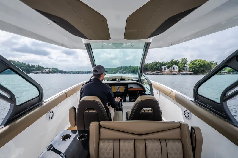 Slide: The Image of 2026 Monterey Elite 30 OB boat interior with driver on a scenic lake. - 12