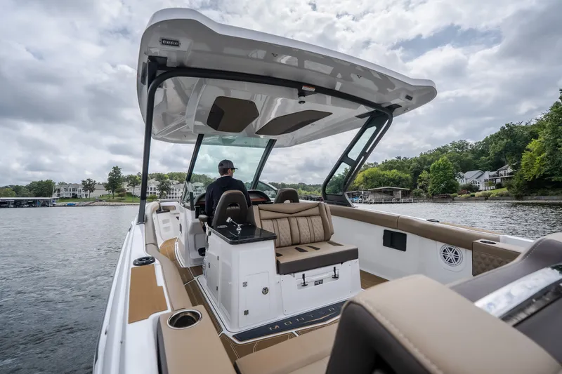 Slide: The Image of 2026 Monterey Elite 30 OB boat cruising on a scenic lake with lush greenery. - 6