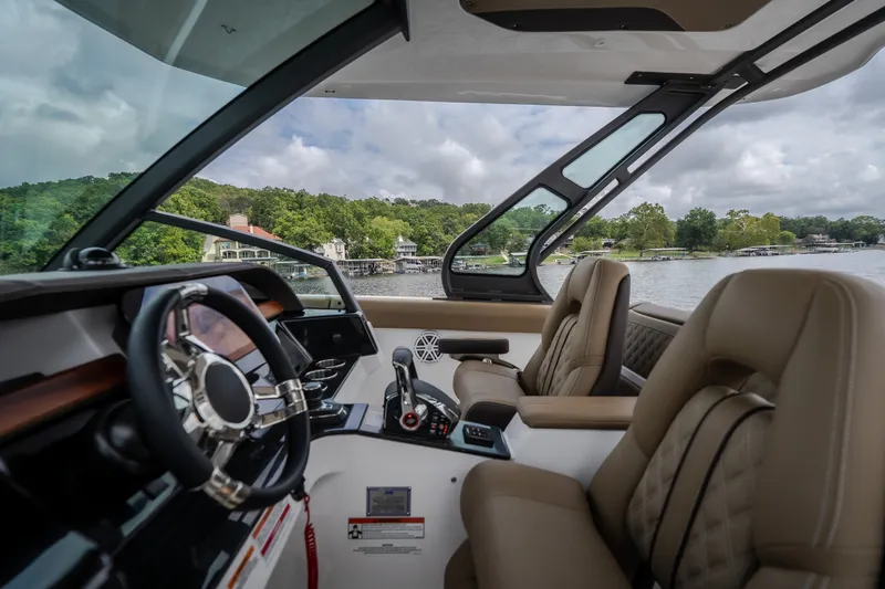 Slide: The Image of Interior view of 2026 Monterey Elite 30 OB boat with luxurious seating and scenic lake backdrop. - 20