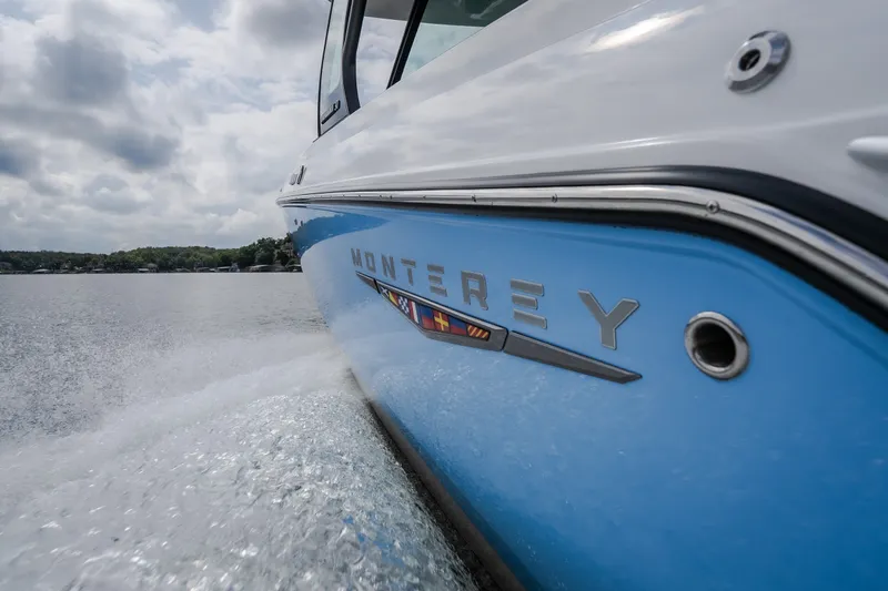 Slide: The Image of 2026 Monterey Elite 30 OB boat cruising on a lake under cloudy skies. - 53
