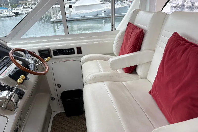 Slide: The Image of 2005 Sea Ray 480 Motor Yacht helm with white seating and red cushions. - 8