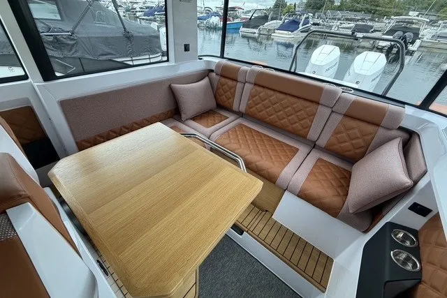 Slide: The Image of Luxurious interior of 2025 Axopar 37 XC Cross Cabin with plush seating and wooden table. - 24