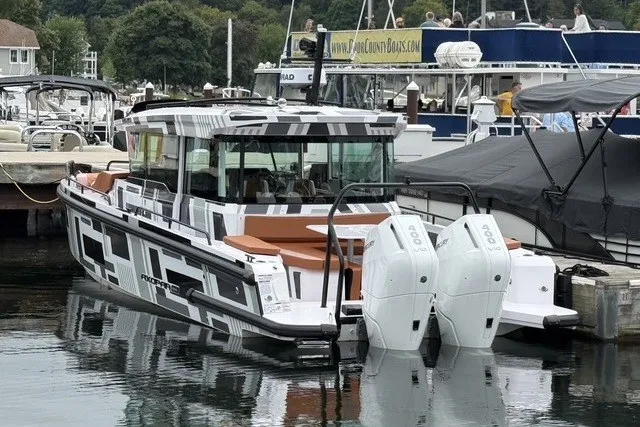 Slide: The Image of 2025 Axopar 37 XC Cross Cabin boat docked, featuring sleek design and dual outboard engines. - 2