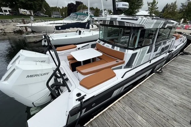 Slide: The Image of 2025 Axopar 37 XC Cross Cabin boat docked, featuring sleek design and Mercury engines. - 10