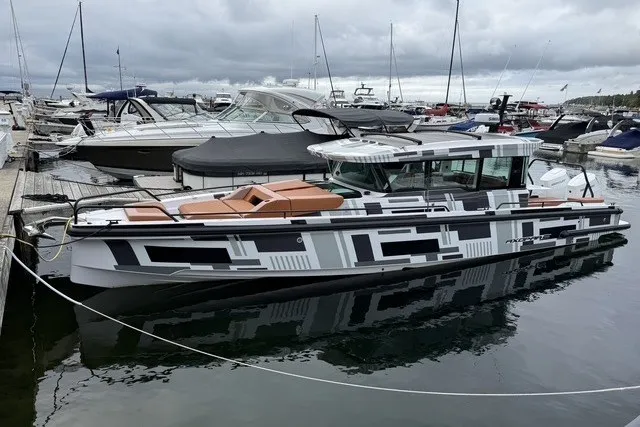 Slide: The Image of 2025 Axopar 37 XC Cross Cabin boat docked in a marina, featuring modern design. - 0