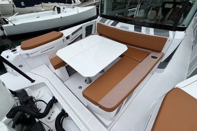 Slide: The Image of 2025 Axopar 37 XC Cross Cabin boat with brown seating and white table. - 13