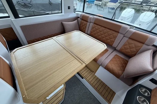Slide: The Image of 2025 Axopar 37 XC Cross Cabin interior with elegant seating and wooden table. - 25