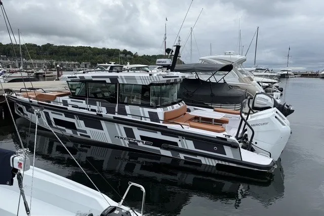 Slide: The Image of 2025 Axopar 37 XC Cross Cabin boat docked in a marina, featuring sleek design and modern amenities. - 1