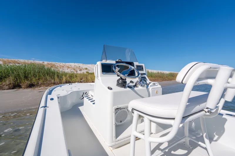Slide: The Image of 2013 Yellowfin 24 Bay boat with white seating, docked near sandy shore under clear blue sky. - 12