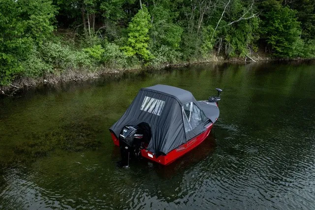 Slide: The Image of A red boat with a black canopy floats in calm, wooded waters. - 5