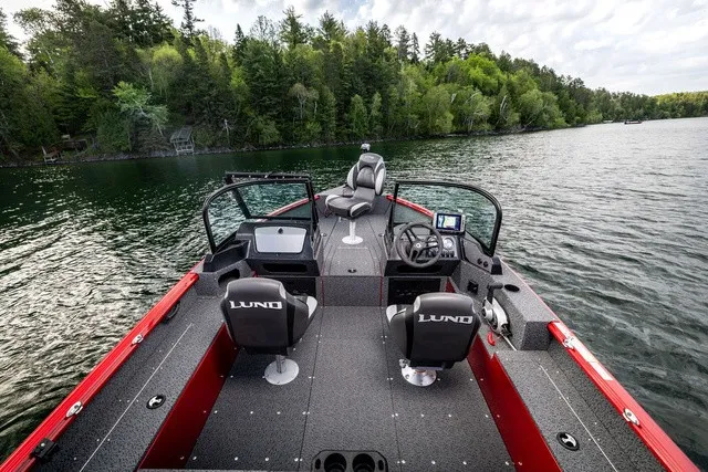 Slide: The Image of The image shows a Lund 1700 Adventure Sport boat on a calm lake with a wooded shoreline. - 6