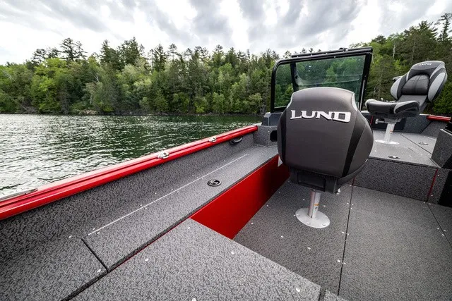 Slide: The Image of A Lund 1700 Adventure Sport boat on a calm lake with a wooded shoreline in the background. - 8