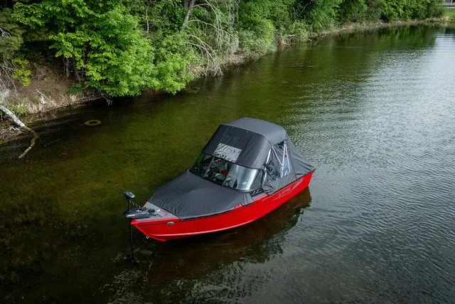 Slide: The Image of A red boat with a black canopy floats in calm, wooded waters. - 4