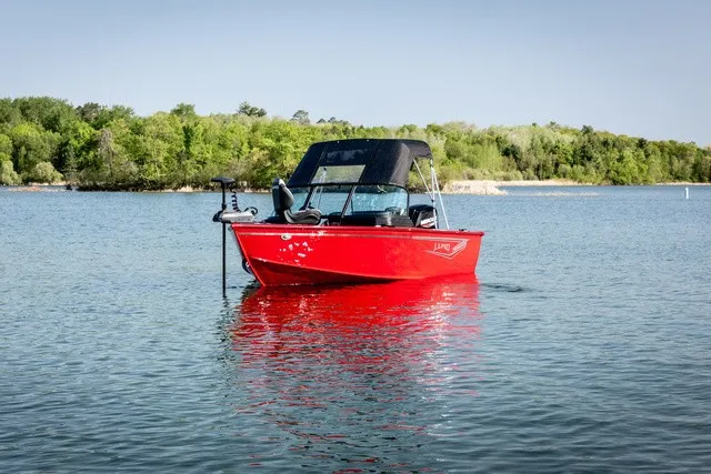 Slide: The Image of A red boat floating on a calm lake, surrounded by green trees. - 1