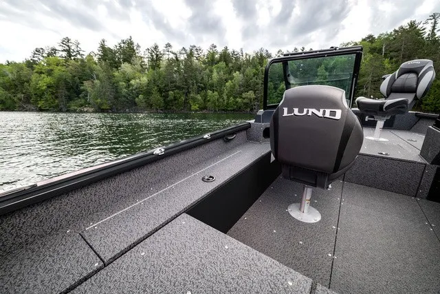 Slide: The Image of The image shows a Lund 1700 Adventure Sport boat on a calm lake with a wooded shoreline. - 8