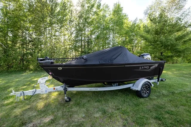 Slide: The Image of A 2027 Lund 1700 Adventure Sport boat on a trailer, surrounded by trees. - 2