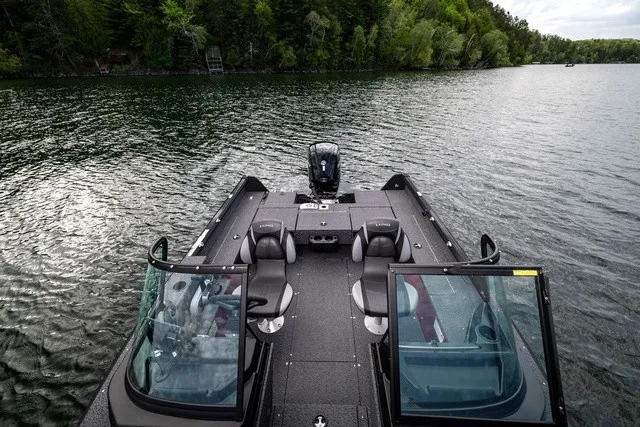 Slide: The Image of The image shows a Lund 1700 Adventure Sport boat on a calm lake with a wooded shoreline. - 7