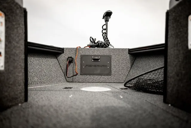Slide: The Image of The image shows the interior of a Lund 1875 Fisherman boat with gray carpeting and a control unit. - 11