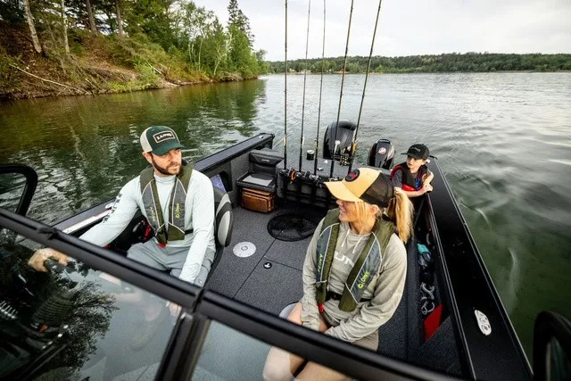 Slide: The Image of Three people sit in a Lund 1875 Fisherman boat on a calm lake, surrounded by trees. - 9