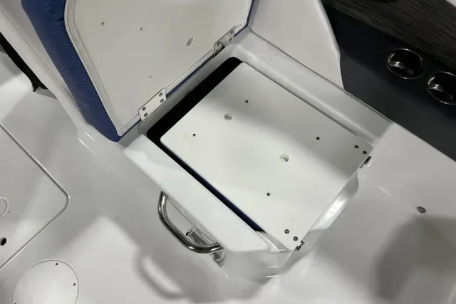 Slide: The Image of An open storage compartment on a 2025 Scarab 255 LX boat, featuring a metal handle. - 14