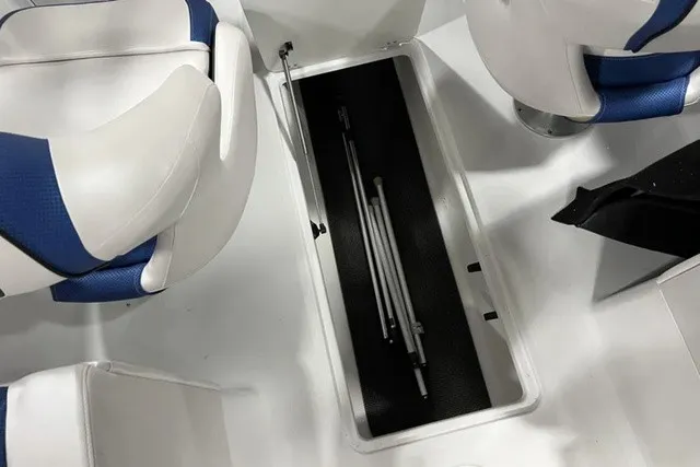 Slide: The Image of The image shows the storage compartment of a 2025 Scarab 255 LX boat with white and blue seats. - 18