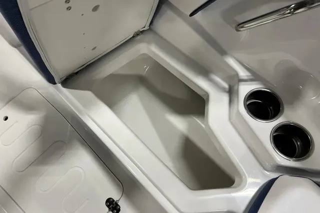 Slide: The Image of The image shows an open storage compartment on a 2025 Scarab 255 LX boat with cup holders. - 28