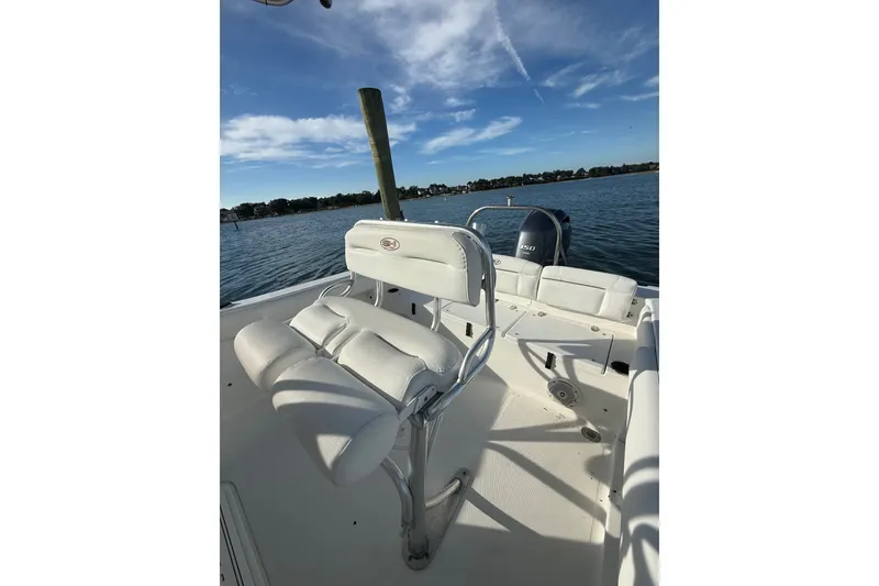 Slide: The Image of 2018 Sea Hunt Ultra 211 boat interior with seating, on a sunny day by the water. - 17