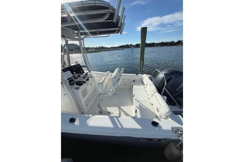 Slide: The Image of 2018 Sea Hunt Ultra 211 boat docked by the water, featuring a sleek console and seating. - 19