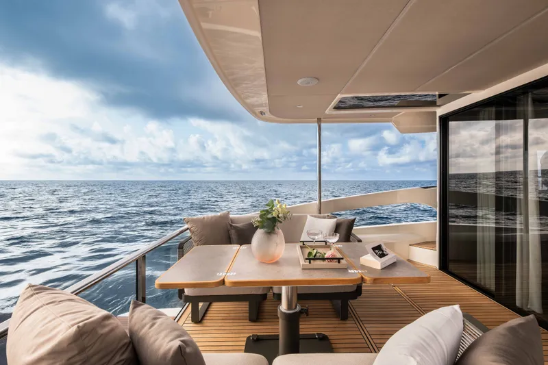 Slide: The Image of The 2027 Absolute 50 Navetta features an elegant deck with a table, cushions, and ocean view. - 9