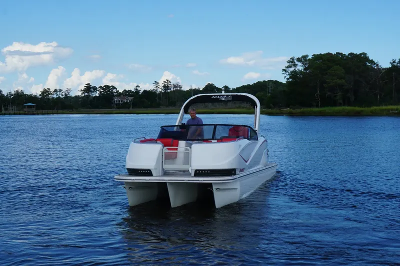 Slide: The Image of 2021 Amara pontoon boat cruising on a serene lake with lush greenery. - 6