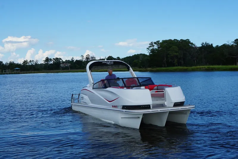 Slide: The Image of 2021 Amara pontoon boat cruising on a serene lake with lush greenery. - 7