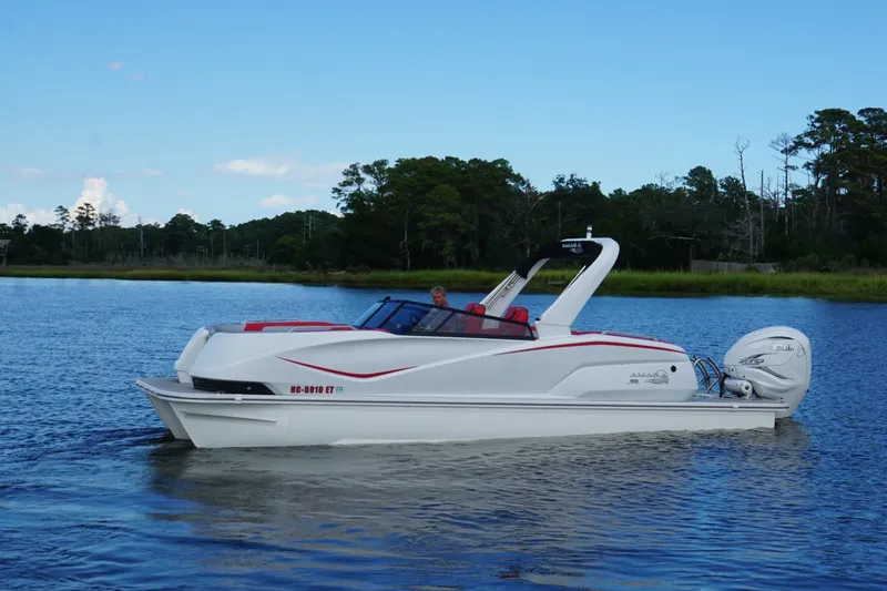 The Image of 2021 Amara pontoon boat cruising on a serene lake with lush greenery. - 1