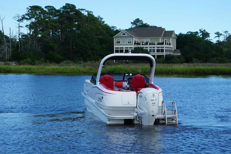 Slide: The Image of 2021 Amara pontoon boat cruising on a serene lake near a large house. - 4