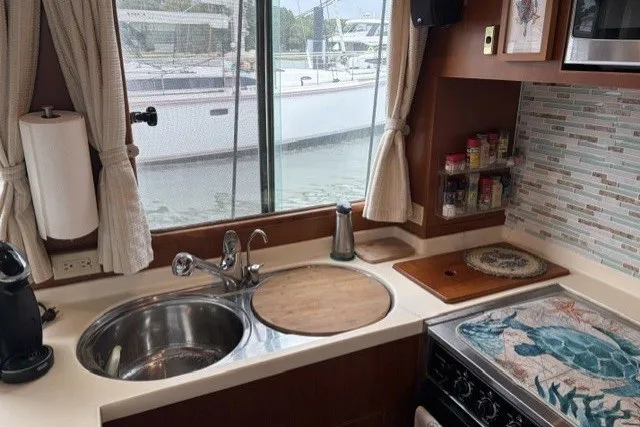 Slide: The Image of Cozy kitchen in 2012 North Pacific Yachts 43, featuring sink, stove, and window view. - 11
