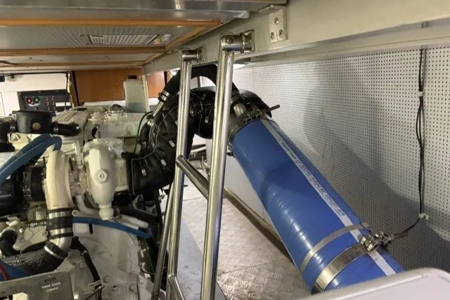 Slide: The Image of Engine room of a 2012 North Pacific Yachts 43, featuring blue exhaust hose and mechanical components. - 97
