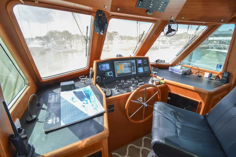 Slide: The Image of Interior helm of 2012 North Pacific Yachts 43, featuring navigation equipment and wooden steering wheel. - 6
