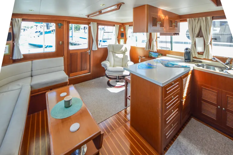 Slide: The Image of Interior of 2012 North Pacific Yachts 43, featuring cozy seating and a compact kitchen area. - 3