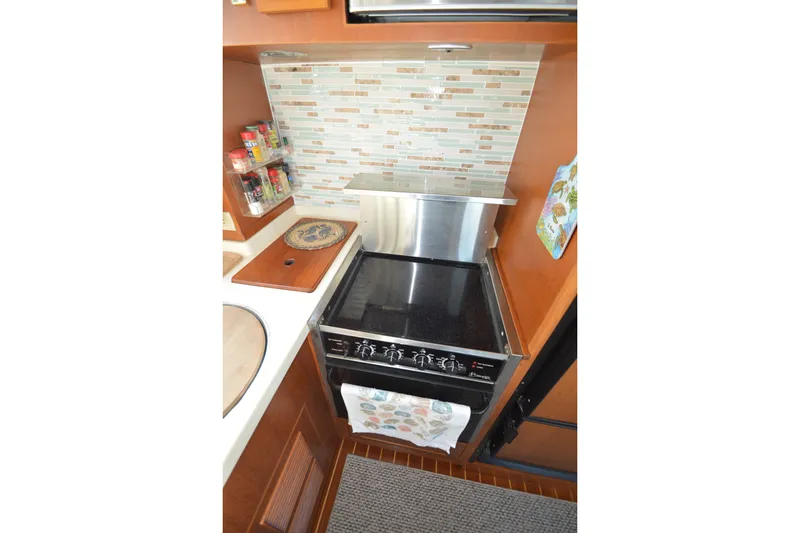 Slide: The Image of Compact kitchen area in a 2012 North Pacific Yachts 43, featuring a stove and backsplash. - 55