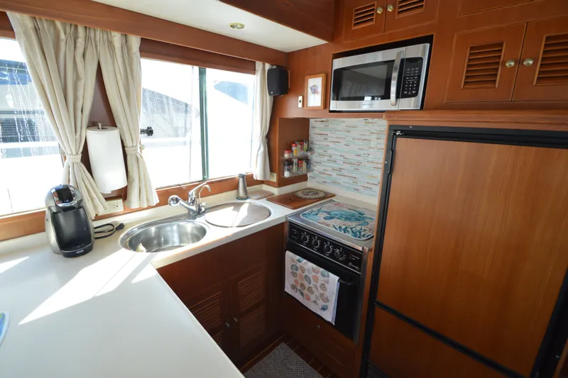 Slide: The Image of 2012 North Pacific Yachts 43 kitchen with sink, stove, microwave, and wooden cabinetry. - 5