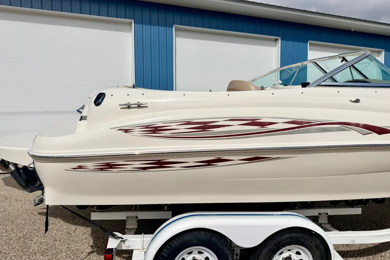 Slide: The Image of 2000 Sea Ray 210 Sundeck boat on trailer, parked near blue building. - 11
