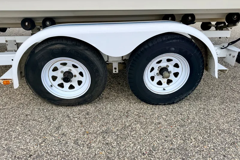 Slide: The Image of Trailer wheels for 2000 Sea Ray 210 Sundeck on asphalt surface. - 74